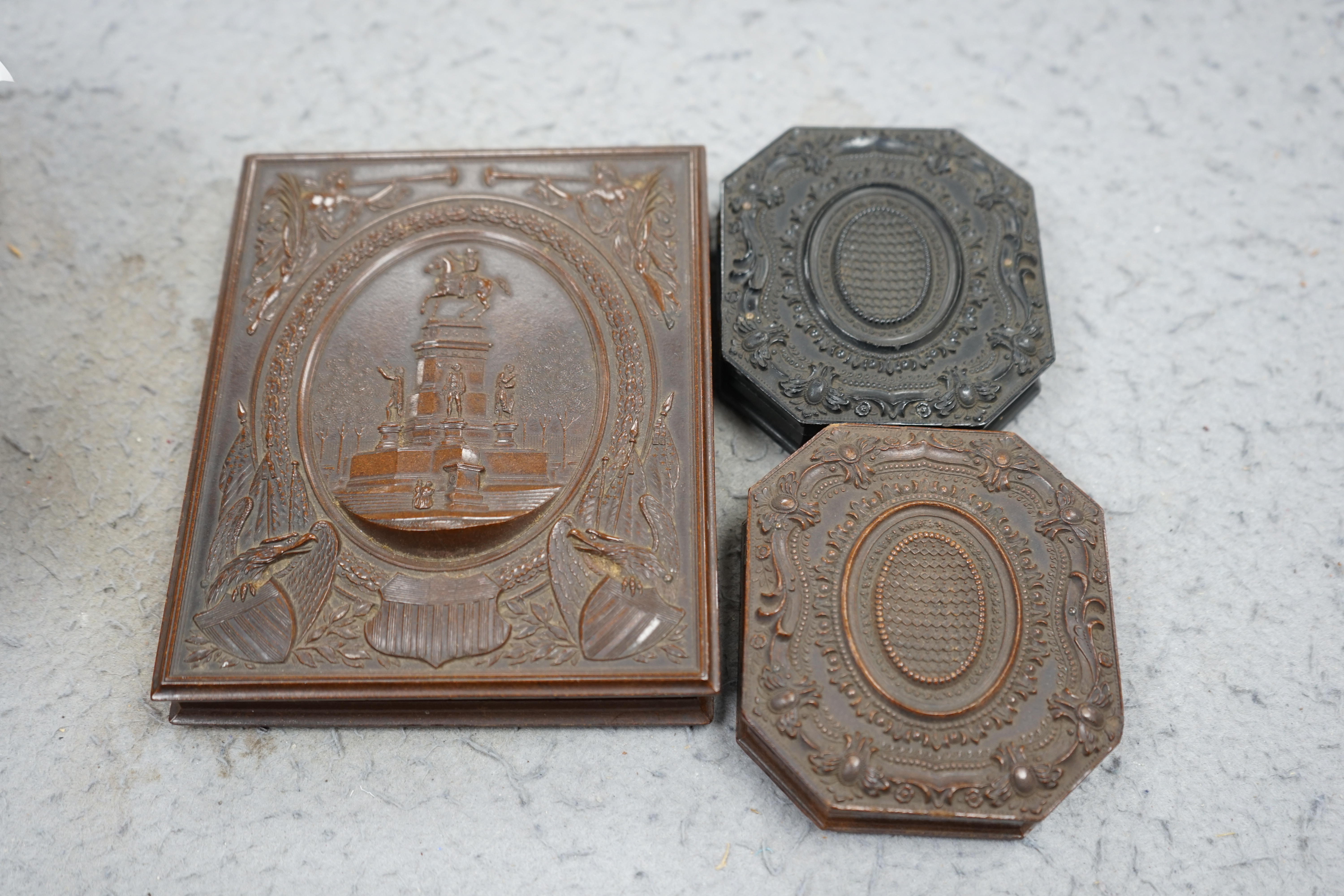 A pair of Peck & Co. sixth-plate ambrotype composite moulded cases, together with a Washington Monument phenolic cased ambrotype, largest 16 x 13cm. (3). Condition - fair